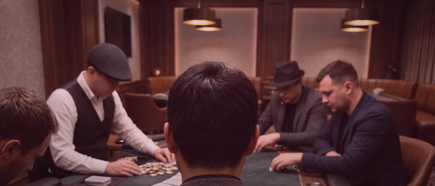 A hand of euchre partway through, cards held close to the chest above green baize.